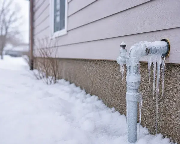 Frozen outdoor pipe coated in ice during a hard freeze