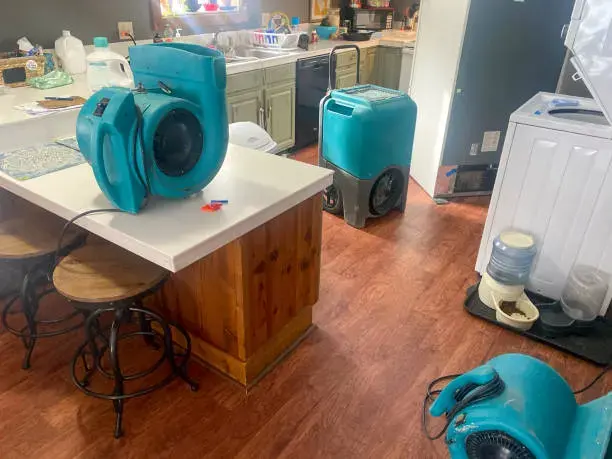 Air movers and an LGR dehumidifier drying a Sugar Land kitchen
